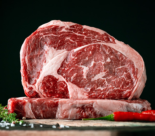 Raw rib eye beef steak on a black background Spring Creek Special Selection Beef